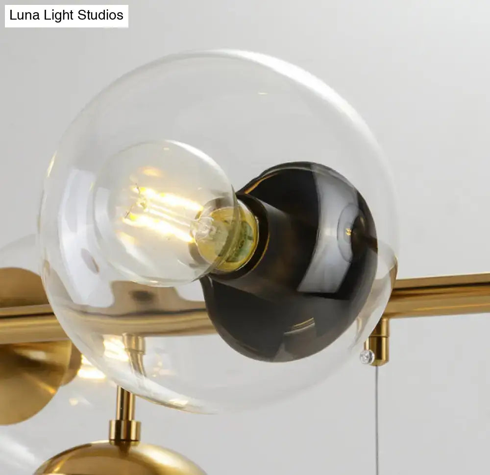 Modern gold metal island pendant with clear glass globe and exposed filament bulb on polished brass hardware