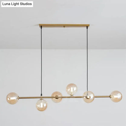 Modern gold metal island pendant with five amber glass globes and black cords for dining room lighting