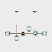 Modern gold metal island pendant with six translucent blue glass spheres suspended from brass ceiling fixtures