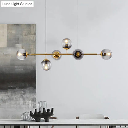 Modern gold metal island pendant with clear and smoky glass globe shades for dining room lighting
