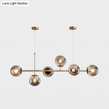 Modern gold metal island pendant with brass chandelier featuring five smoked glass globe bulbs for dining room