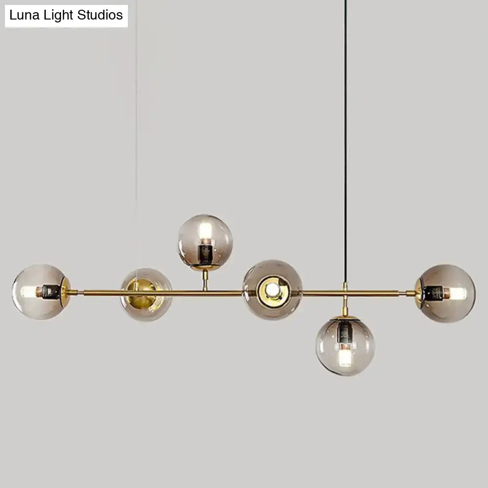 Modern gold metal island pendant with five smoked glass globes and brass accents for dining room illumination