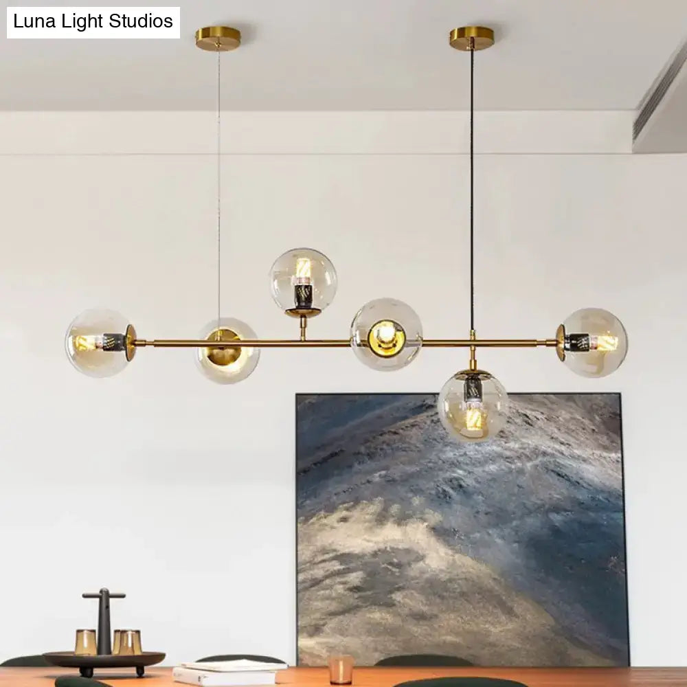 Modern gold metal island pendant with gold-toned chandelier and clear glass globe shades for dining room lighting