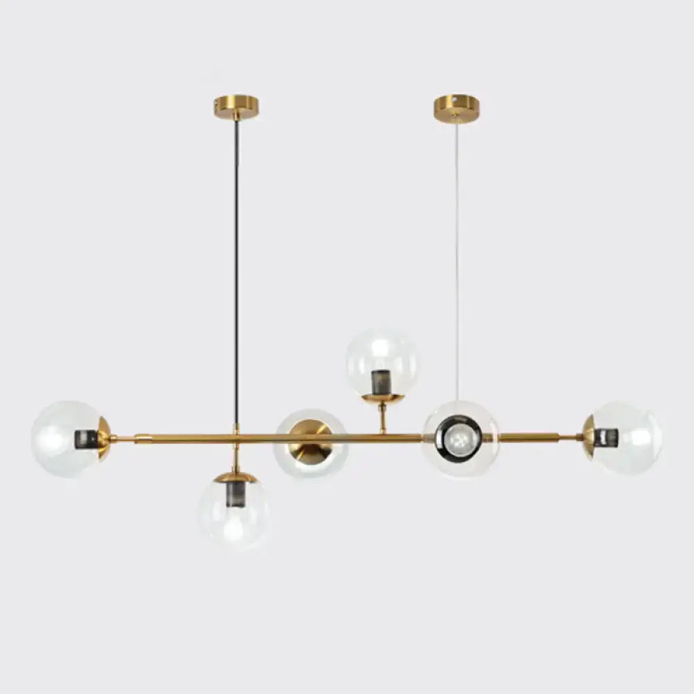 Modern gold metal island pendant with brass chandelier design, clear glass globe bulbs, and black cord accents for dining room