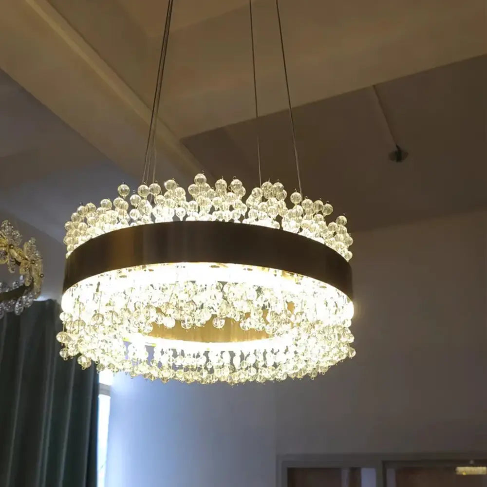 A modern gold metal led chandelier with a circular frame and cascading clear crystal droplets for dining room decorbites gold metal
