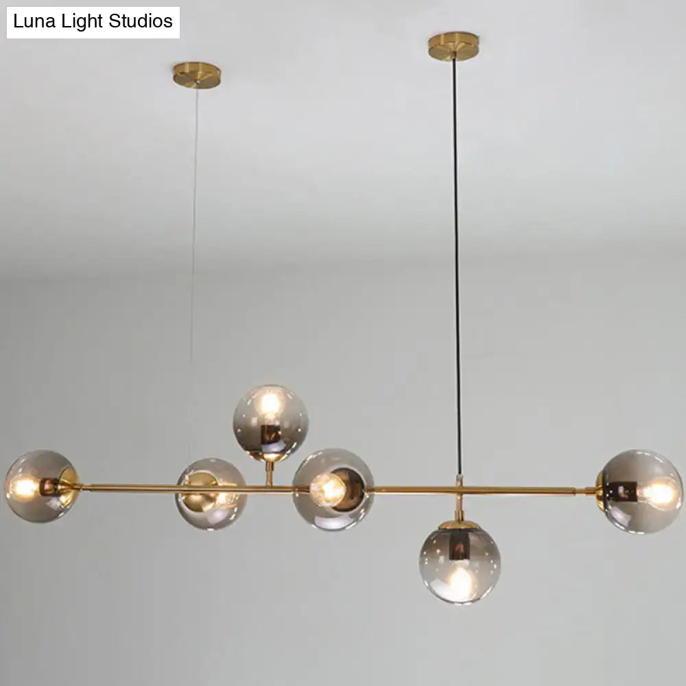 Modern gold metal pendant lighting with six smoked glass globe bulbs suspended by black cords for dining room use