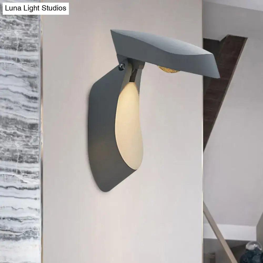 Modern gold metal wall light bedside fixture with sleek gray wall sconce and warm light diffused through curved shade