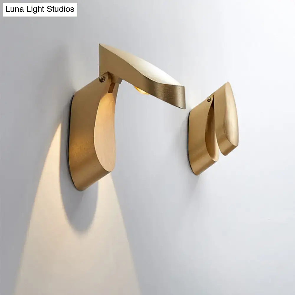 Modern gold metal wall light bedside fixture with minimalist sculptural design and warm light beam