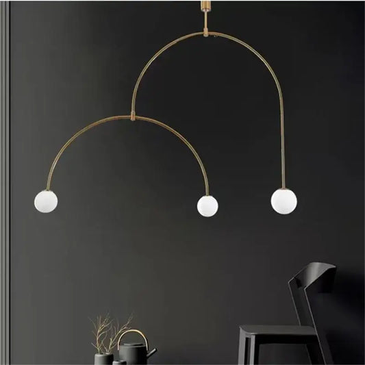 Modern gold minimalist iron chandelier featuring a brass arched pendant light with three white glass bulbs for dining room decorbites black