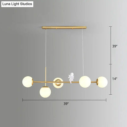 Modo island gold-toned pendant light with five frosted milk white glass globes and central decorative white figurine for restaurants