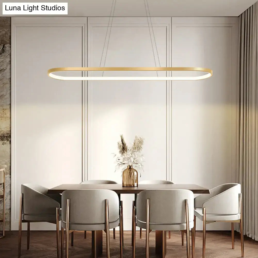 Modern gold oblong led pendant light fixture with chain cord length and warm white color above dining table