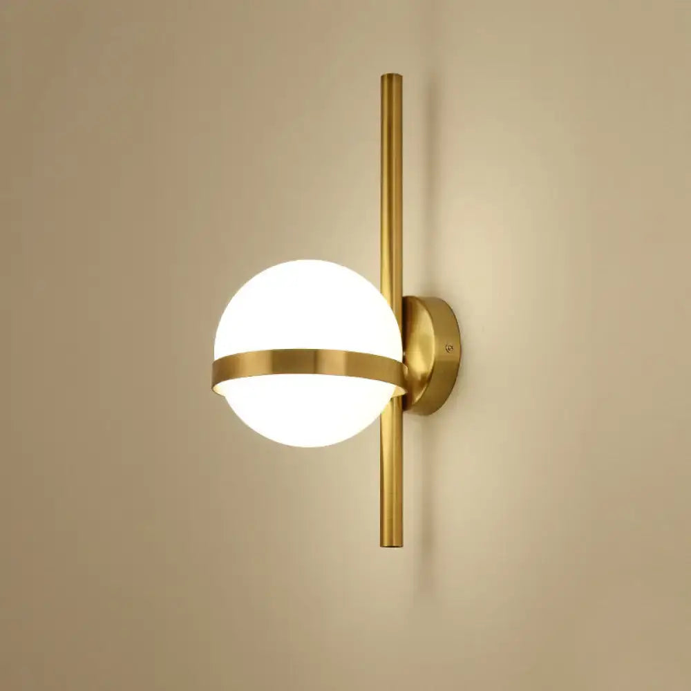 Modern gold wall sconce featuring a gold-toned opal glass orb with a horizontal metallic band for living room lighting