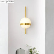 Modern gold opal glass orb wall sconce with a frosted opal glass orb and minimalist metallic gold accents for living room lighting