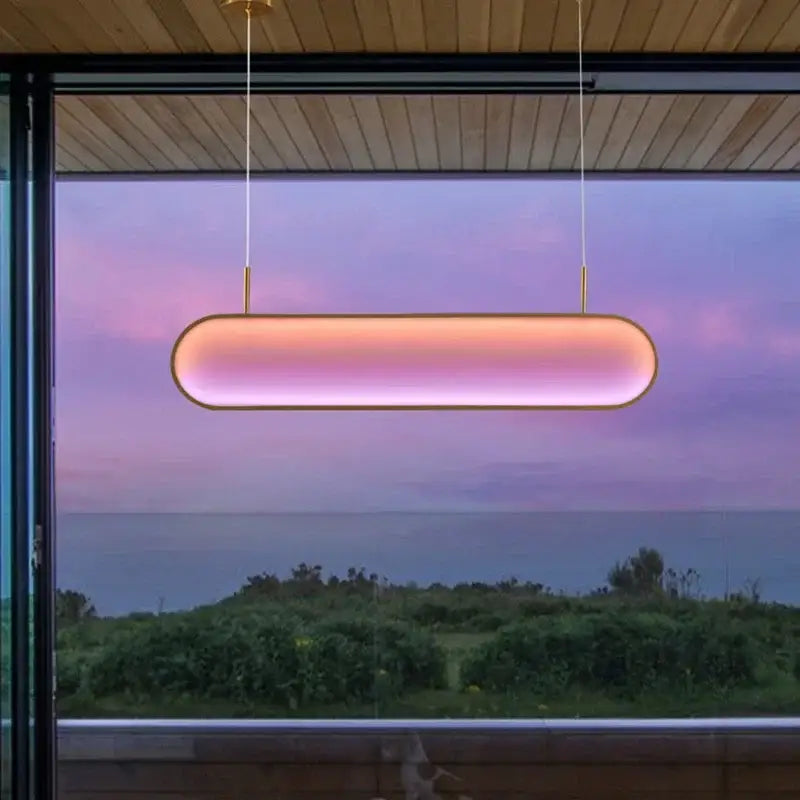 A modern gold oval decorbites led sunset chandelier with warm pink purple gradient glow hanging from wooden ceiling