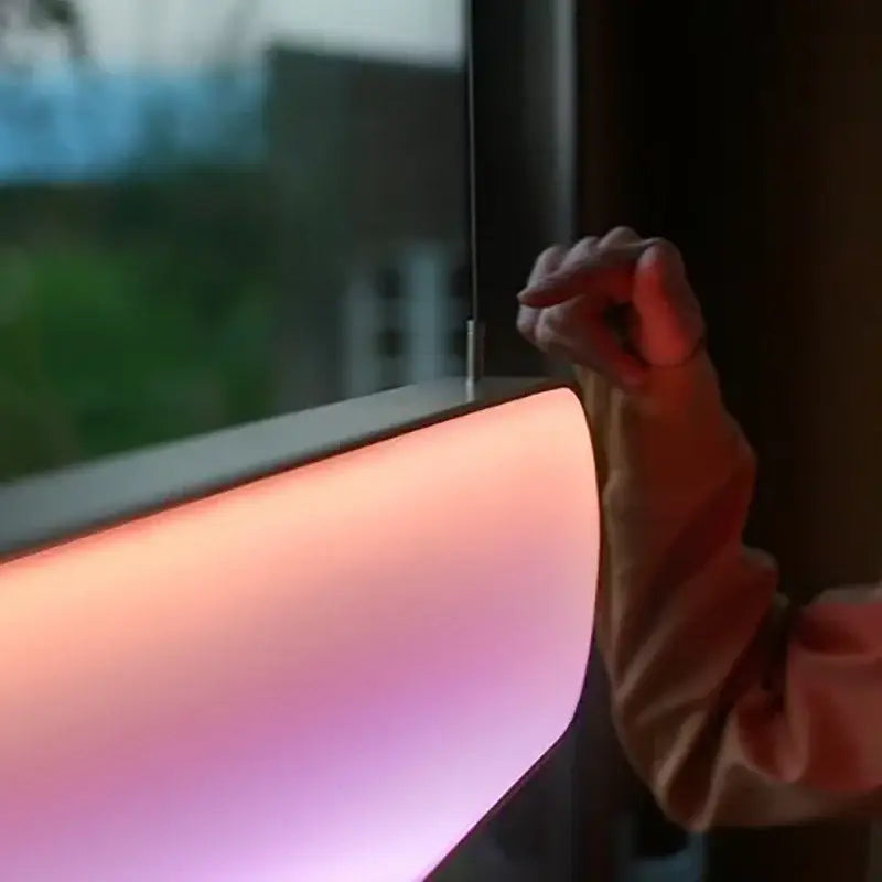 A sleek curved decorbites led sunset oval chandelier with warm pink and orange hues for dining room lighting