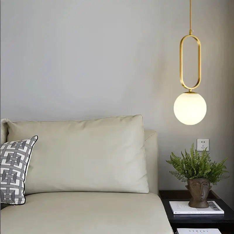 Modern gold pendant lights with a sleek oval frame and frosted glass ball by Decorbites for dining room decor