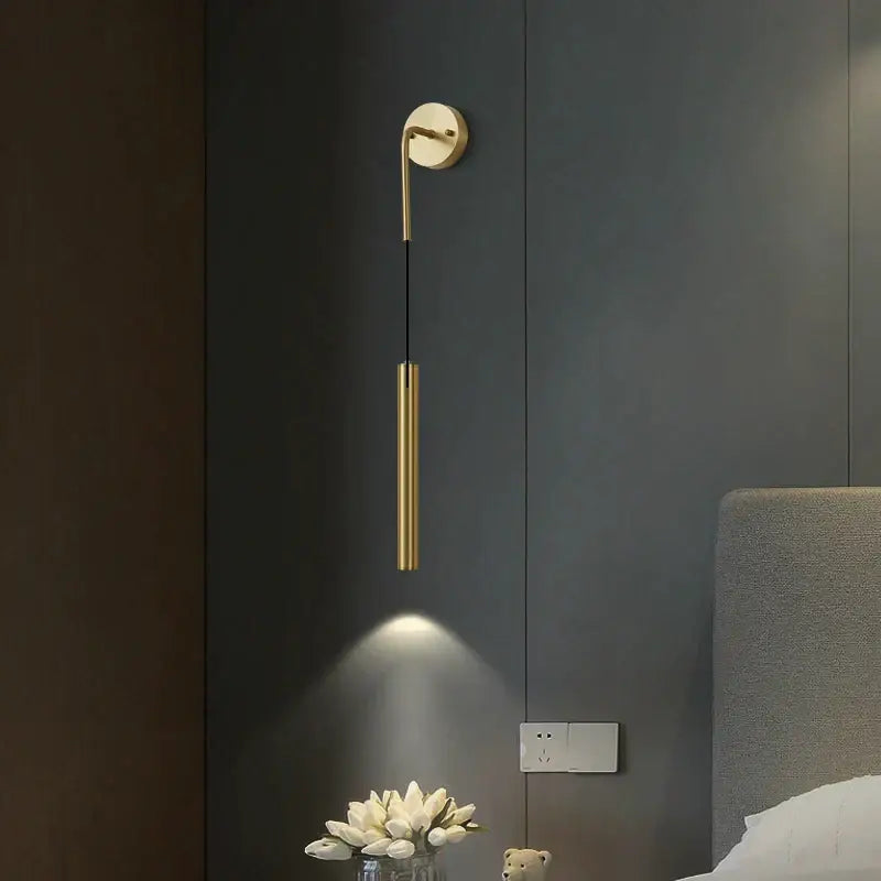 Gold-toned minimalist wall sconce with a sleek cylindrical body and curved arm in modern wall sconce set for bedroom lighting