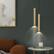 Two sleek cylindrical gold pendant lights hang from the ceiling as part of a modern wall sconce set for bedroom lighting