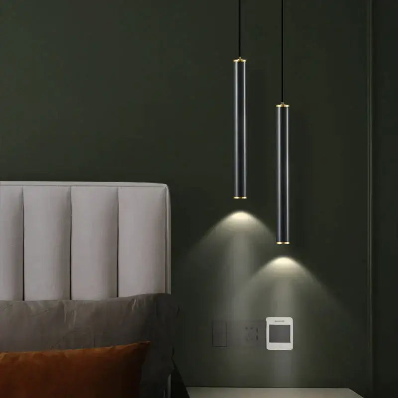 Two sleek matte black and gold cylindrical pendant lights from a modern gold wall sconce set for bedroom lighting