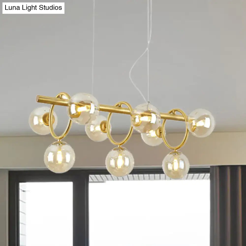 Gold-toned DecorBites™ Nordic style pendant light with clear cognac glass globe bulbs and nine lights on horizontal bar