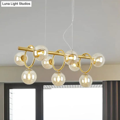 Gold-toned DecorBites™ Nordic style pendant light with clear cognac glass globe bulbs and nine lights on horizontal bar