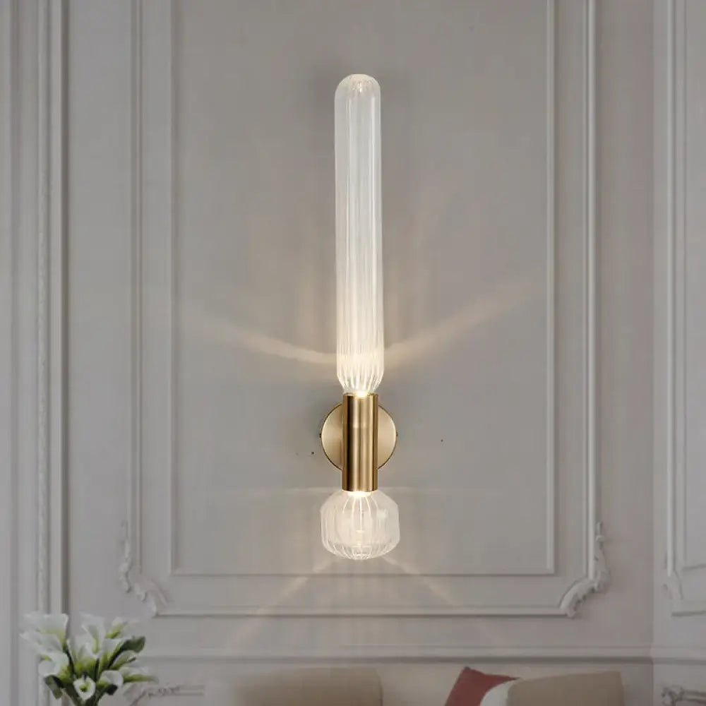 Modern gold ribbed glass wall lighting fixture with translucent cylinder and crystal base on brushed brass backplate