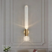 Modern gold ribbed glass wall lighting fixture with translucent cylinder and crystal base on brushed brass backplate