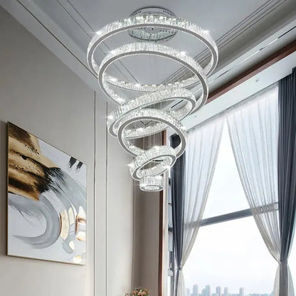 A modern gold decorbites crystal led chandelier with spiral concentric crystal rings emitting elegant living room light