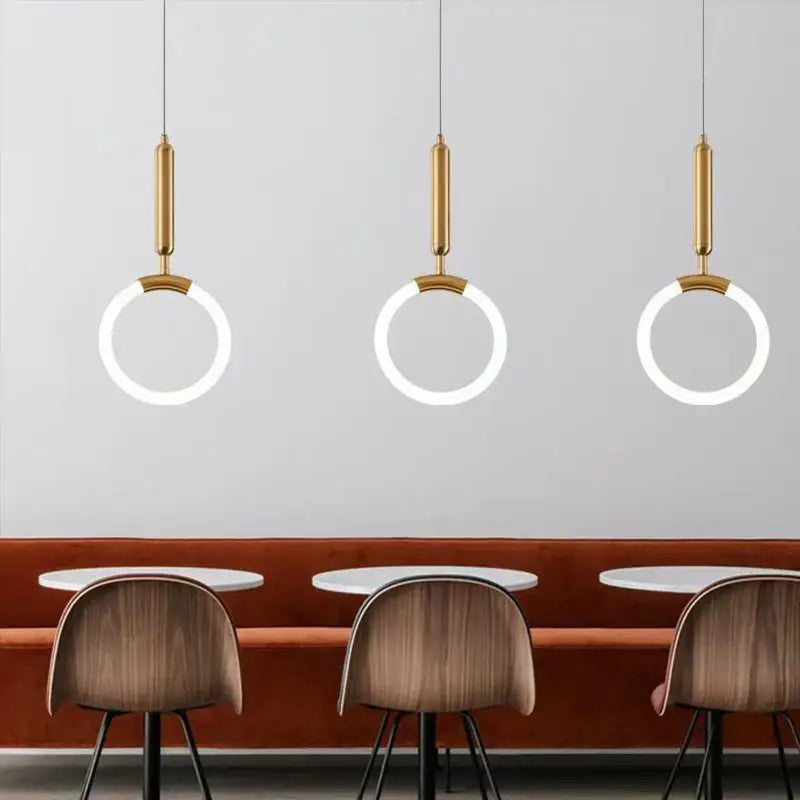 Three modern decorbites gold ring pendant lights with gold-finished cylindrical fixtures for minimalist dining room decor