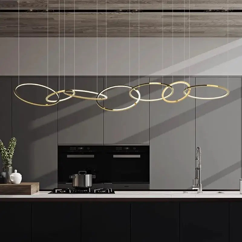 Modern gold round ceiling chandelier with interconnected rings suspended above a sleek kitchen counter decorbites gold round