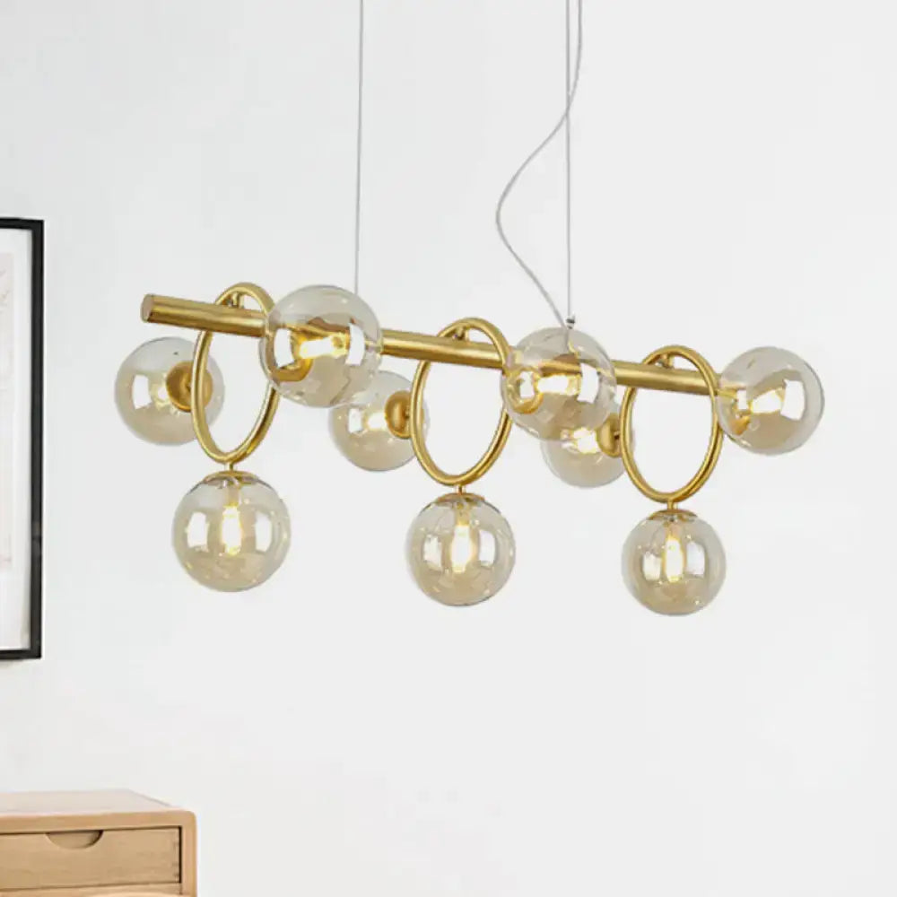 Modern gold round pendant chandelier with cognac glass spheres and circular metal rings in linear design for dining room