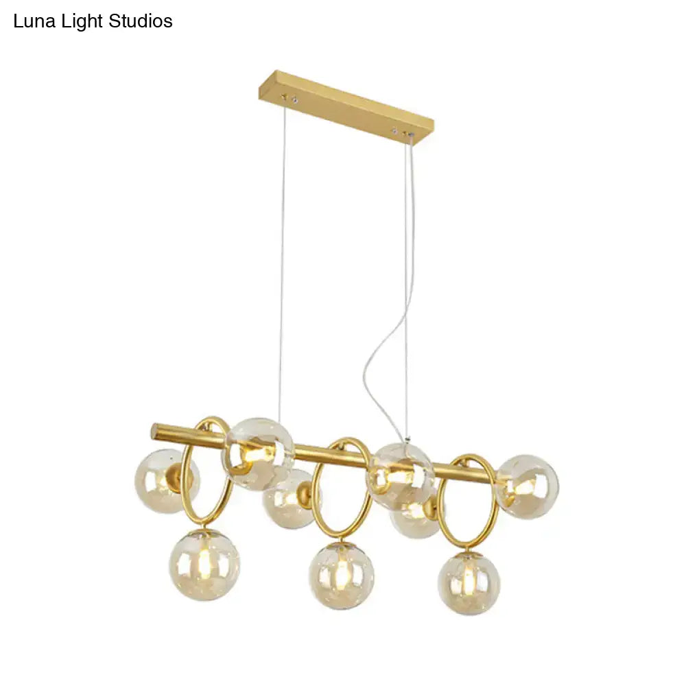Gold-toned modern gold round pendant with cognac glass globes and circular rings in linear design for dining room