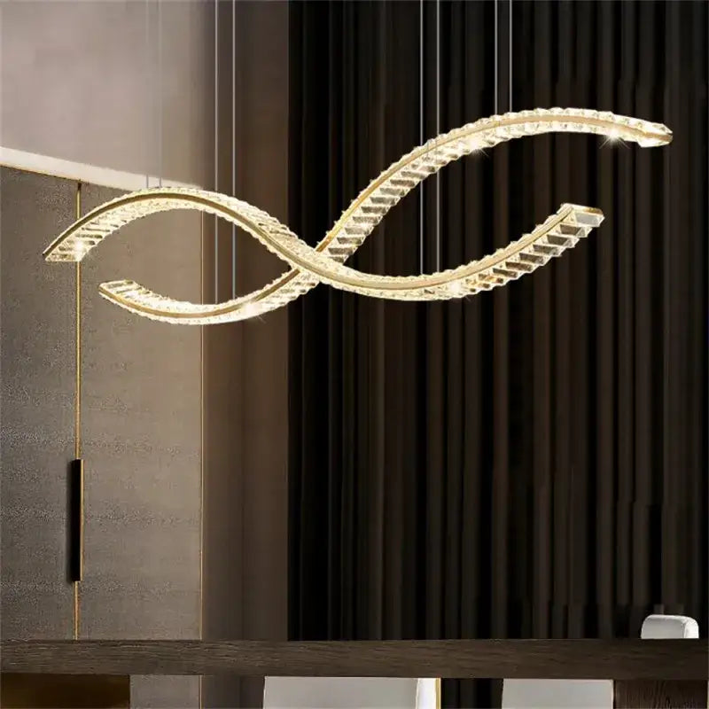 A modern gold s-shaped decorbites crystal led pendant light fixture with clear crystal accents for dining rooms