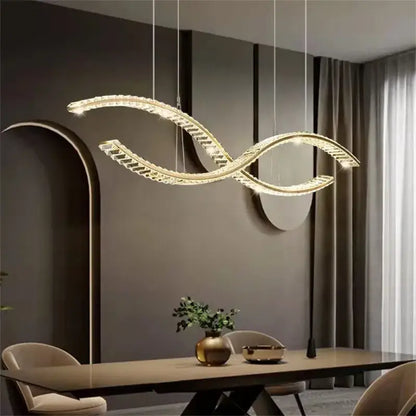 A modern gold-toned decorbites crystal led pendant with a sleek s-shaped design for dining room lighting