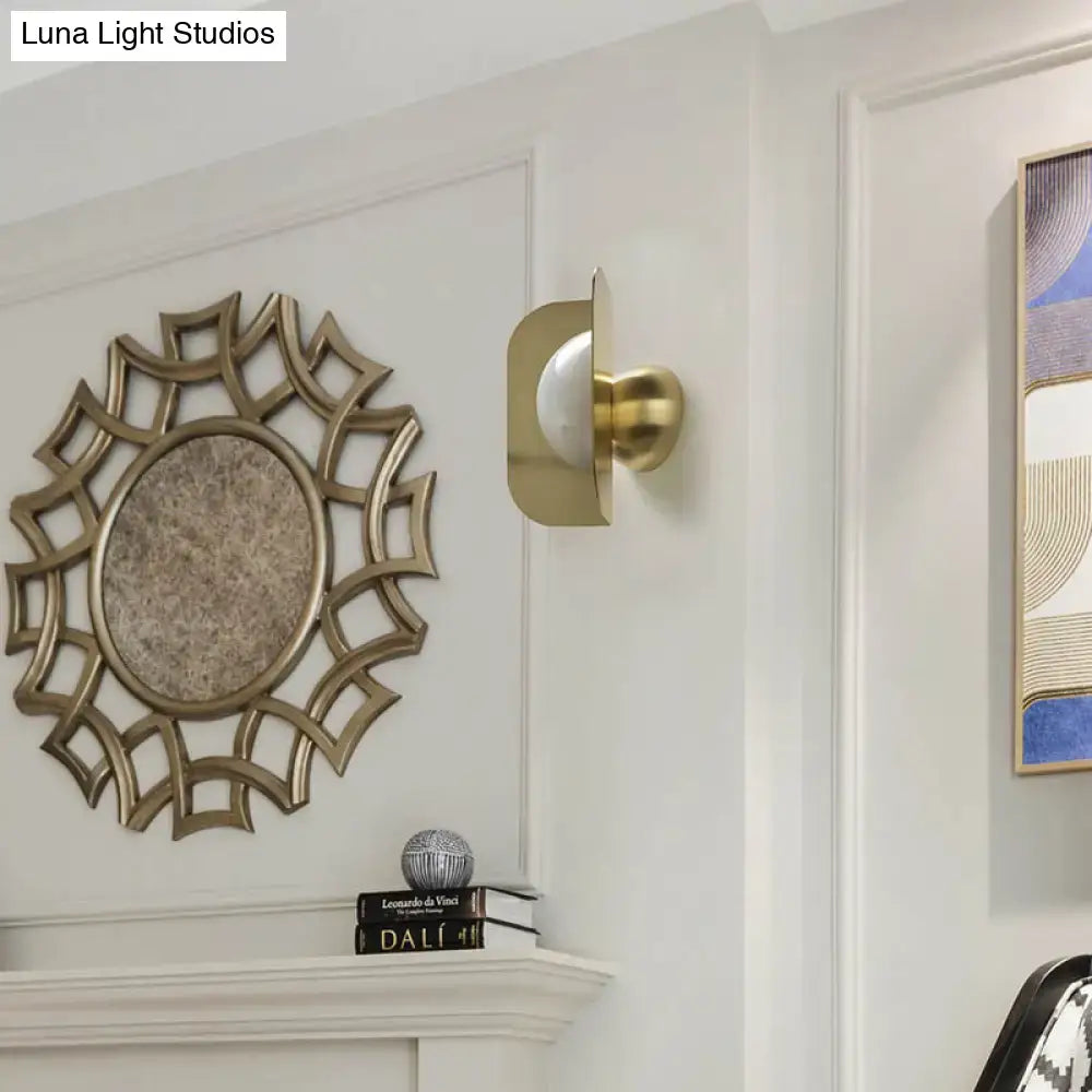 Modern gold sconce light with curved metal shade and frosted glass bulb for elegant bedroom lighting