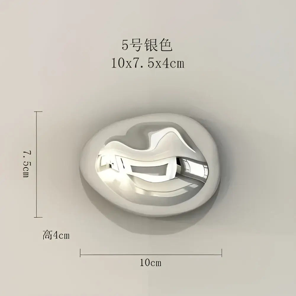Silver-colored oval metal pendant with a smooth reflective surface and abstract design for stone wall ornaments decor