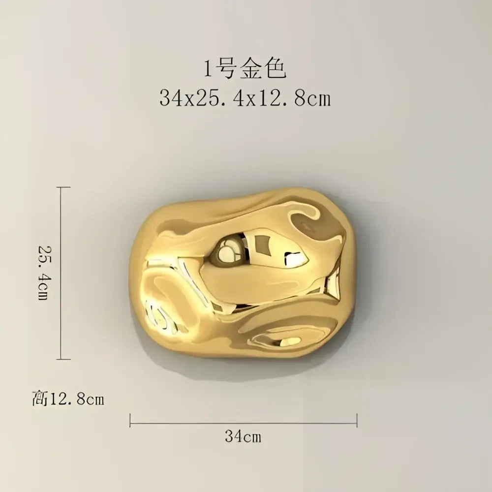 A smooth irregular gold-colored metallic stone wall ornament with a glossy reflective surface for living room decor