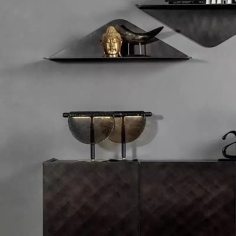 A sleek modern metallic sculpture with semi-circular halves on a decorbites amber glass table lamp for bedroom decor