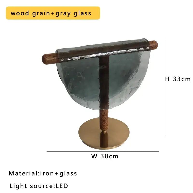 A modern gold and silver decorbites amber glass table lamp with sleek semi-circular wood grain and brass base