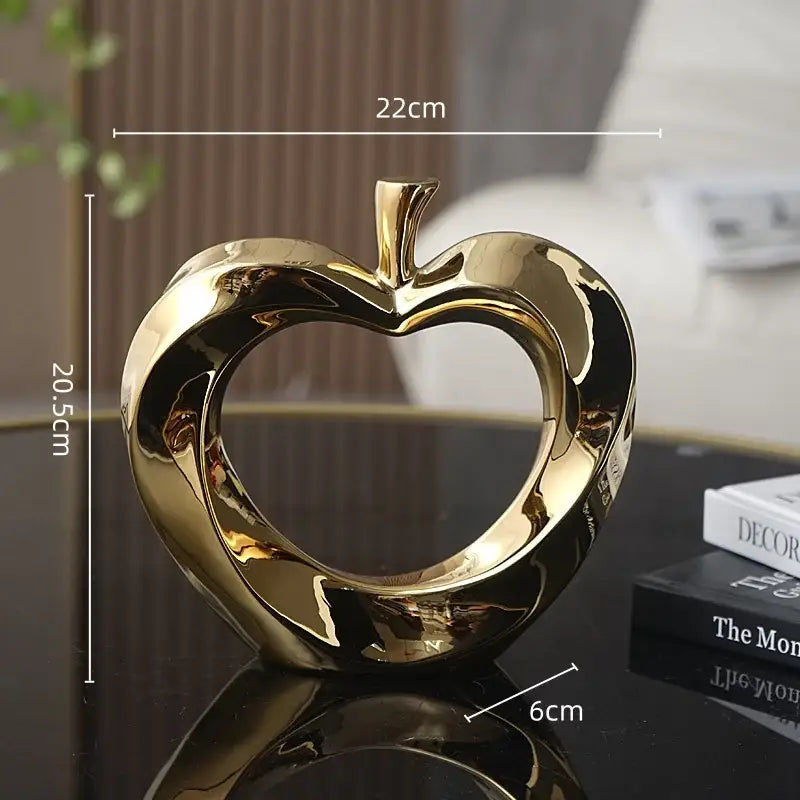 Shiny gold ceramic golden apple sculpture with heart cutout and glossy finish for modern living room decor
