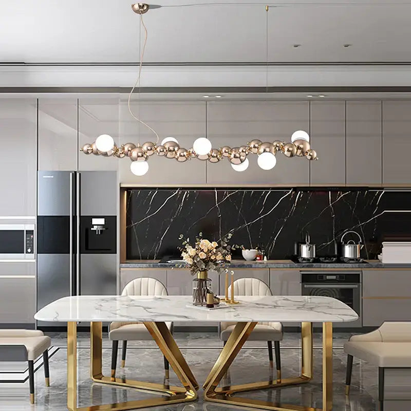 Modern gold and silver dimmable led hanging pendant light with spherical white and metallic orbs above marble table