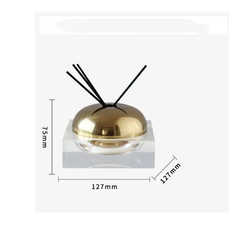 Gold-colored dome-shaped aromatherapy diffuser with black reeds in clear acrylic base for decorbites golden geometry living room