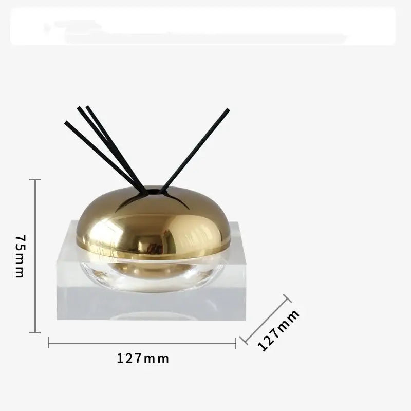 Gold-colored dome-shaped aromatherapy diffuser with black reeds on clear acrylic base for decorbites golden geometry living room decor
