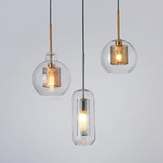 Three modern pendant lights with clear glass shades and gold and silver honeycomb metal inserts for kitchen use