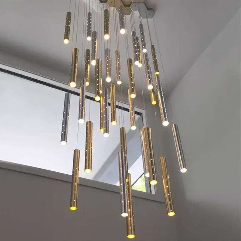 A modern gold silver led pendant light chandelier with cylindrical perforated shades emitting warm light for dining room decorbites gold silver