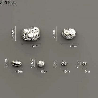 Modern silver metallic rock wall hanging ornaments with polished reflective surface and organic stone-like contours