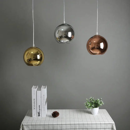 Three spherical pendant lights in gold silver and rose gold glass bubble ball design hang above a kitchen table