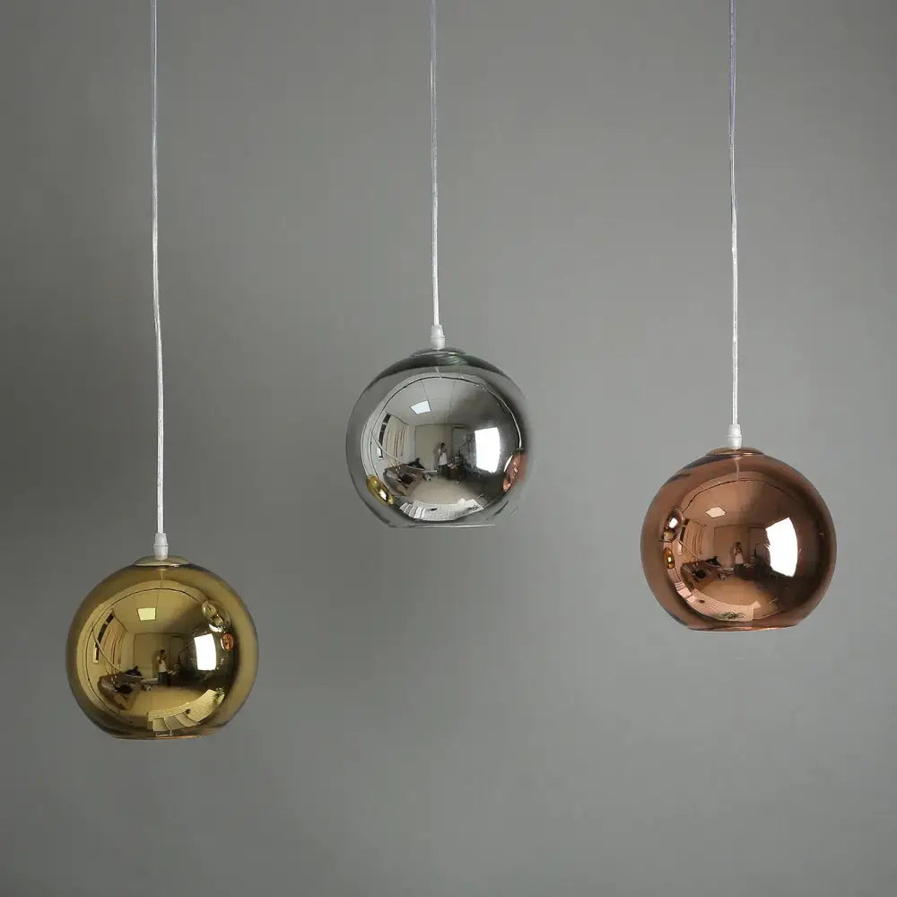 Three glass bubble ball pendant lights in gold silver and rose gold finishes hang from white cords in kitchen decorbites design