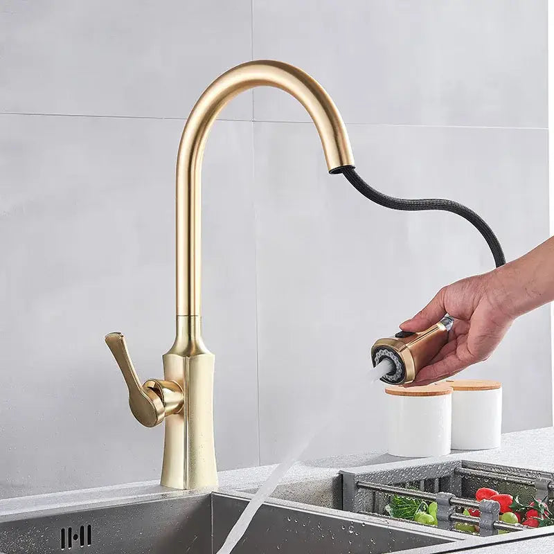 Modern gold single handle kitchen faucet with pull down sprayer featuring a sleek curved gold-toned pull-out spray head