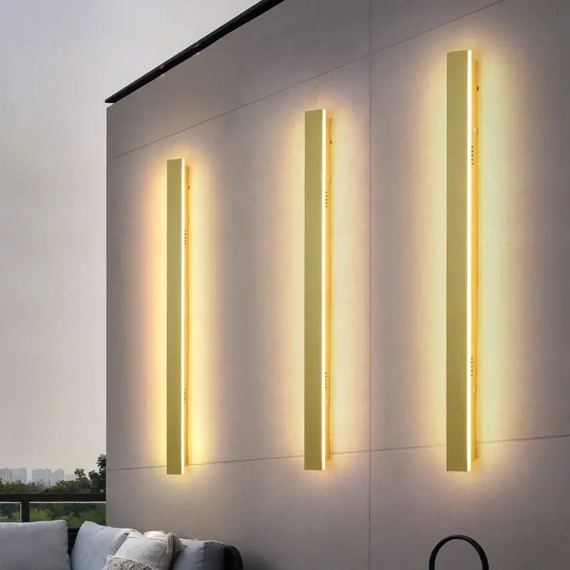Three sleek gold finished modern led wall lamps emit a warm ambient glow for outdoor decorbites led wall use